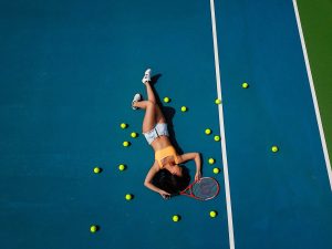 woman in yellow crop top laying down on hard court